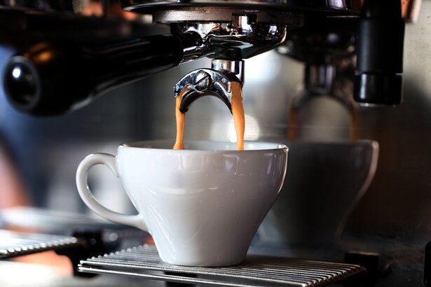Technician repairing a commercial espresso machine in a cafe